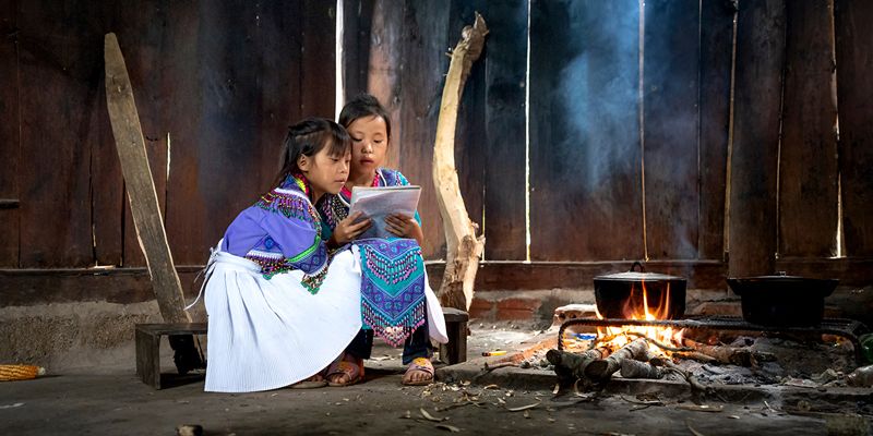 Two little girls looking at a notebook in the home cooking place 